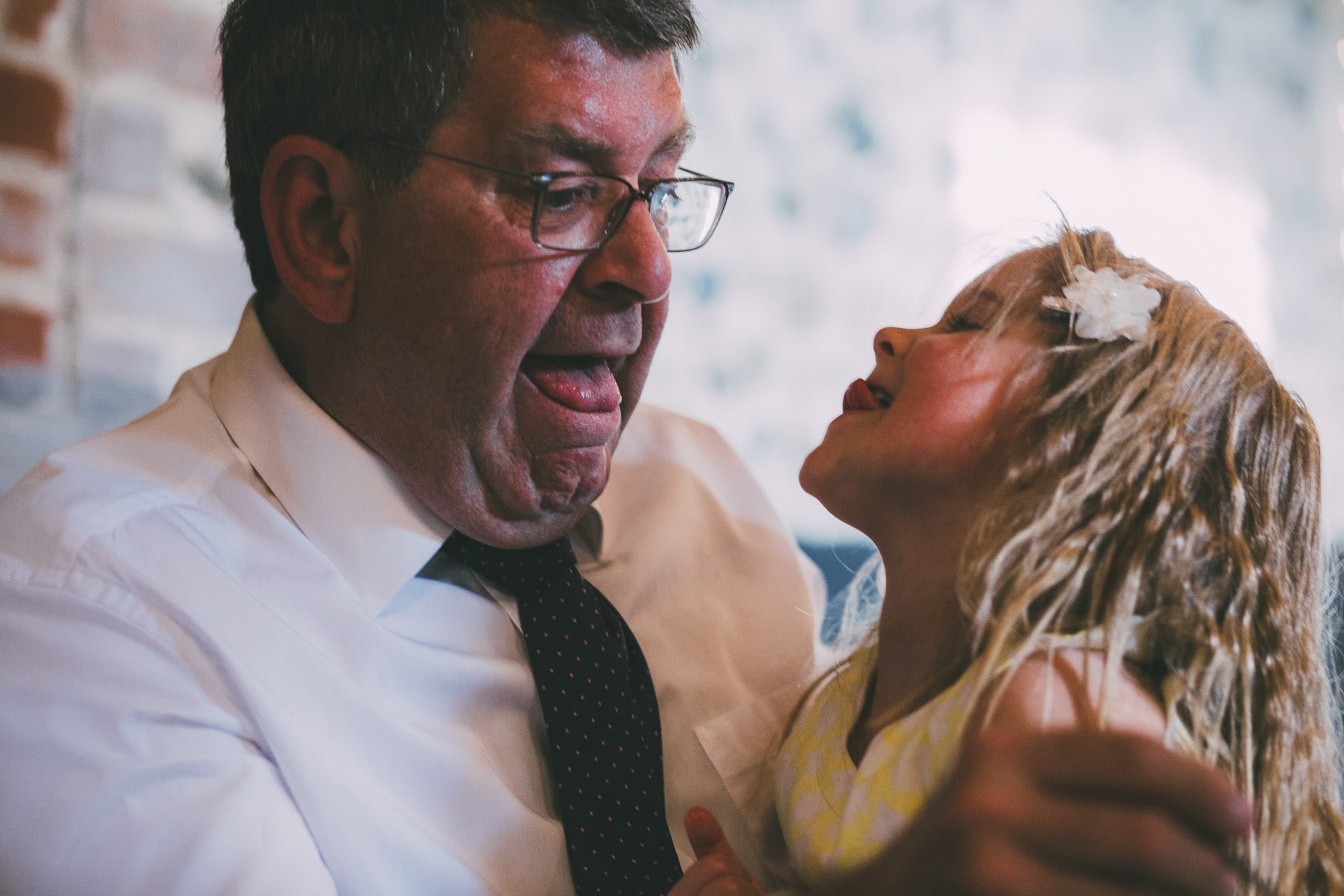 father of bride pulls face with flower girl