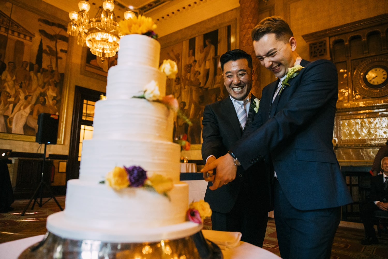 gay couple cut cake whilst laughing